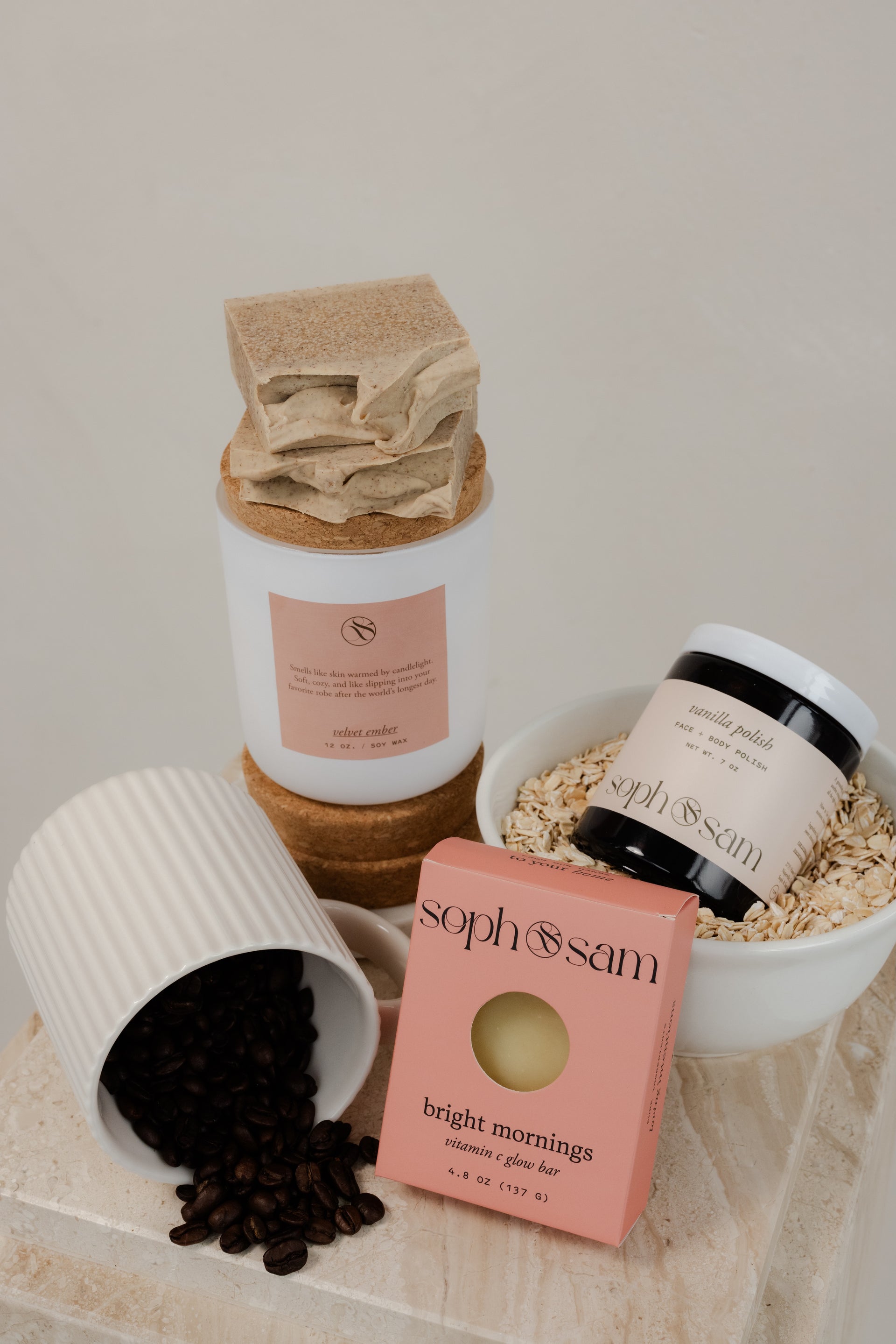 Collection of beauty products including a candle, scrub, and soap on a wooden surface.