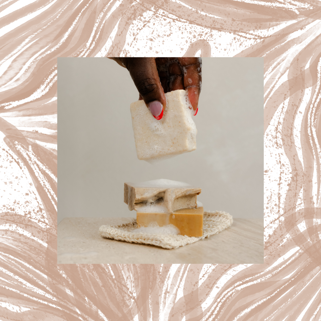 Hand holding a bar of soap above two other bars on a textured surface